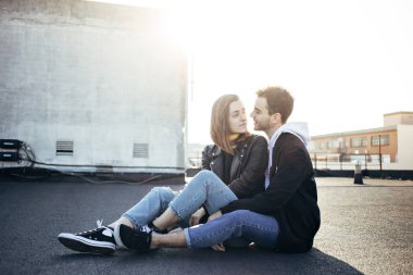 Şık ve trendy kalça hipsters millennials çift, erkek ve kız arkadaşı çatı üstüne batımında, bak birbirlerine sevgiyle otur. Kavram ilişki gol yeni nesil, blogcular stili