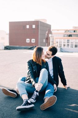 Şık ve trendy kalça hipsters millennials çift, erkek ve kız arkadaşı çatı üstüne batımında, bak birbirlerine sevgiyle otur. Kavram ilişki gol yeni nesil, blogcular stili