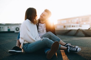 Harika serin ve çekici çift romantik Tarih üzerinde oturmak çatı güzel günbatımı ışık sızıntıları, sarılmak ve sarılmak, bak birbirlerine romantik şekilde gençler aşık, millennials yaşam tarzı çılgın