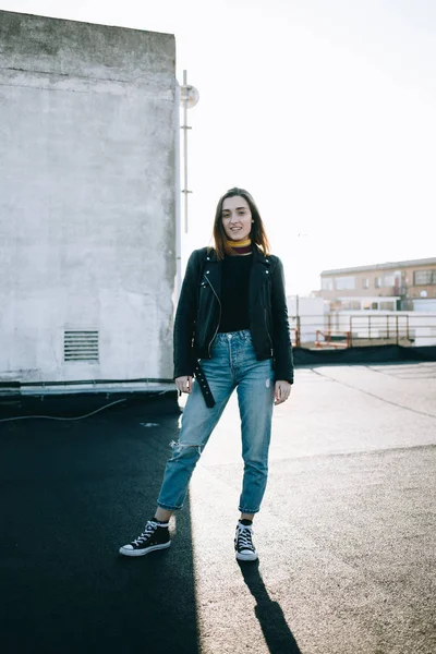 Geniş atış çekici güçlenmiş ve bağımsız kadın güzel veya genç genç moda şık kıyafet, kot pantolon ve deri ceket çatıda'nde Günbatımı poz