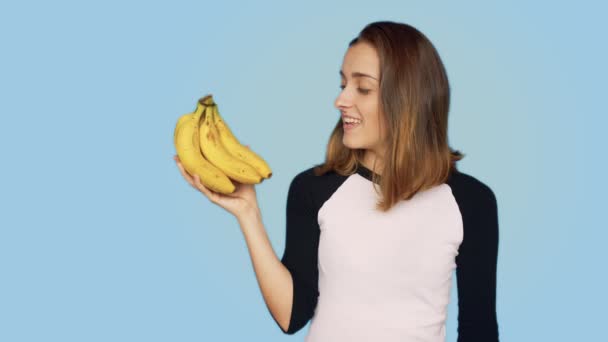 Ganska leende kvinna håller massa bananer — Stockvideo