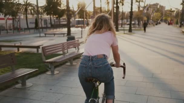 Menina bonita em sua bicicleta urbana vintage ao pôr do sol — Vídeo de Stock