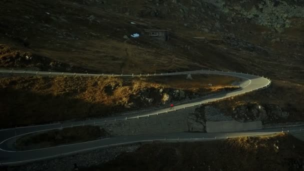 Ciclista de carretera sube por la puesta de sol montaña switchbacks — Vídeo de stock