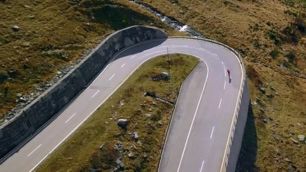 Ciclista de carretera sube por la puesta de sol montaña switchbacks — Vídeo de stock