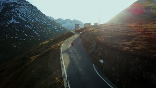 Yol bisikletçisi gün batımında dağ dönüşlerine tırmanıyor. — Stok video