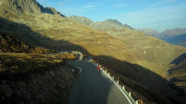 Ciclista de carretera sube por la puesta de sol montaña switchbacks — Vídeos de Stock