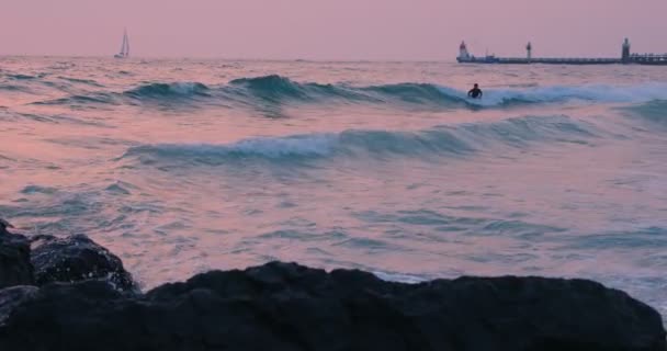 Günbatımı sahilinde dalgıç kıyafetli gençler sörf yapıyor. — Stok video