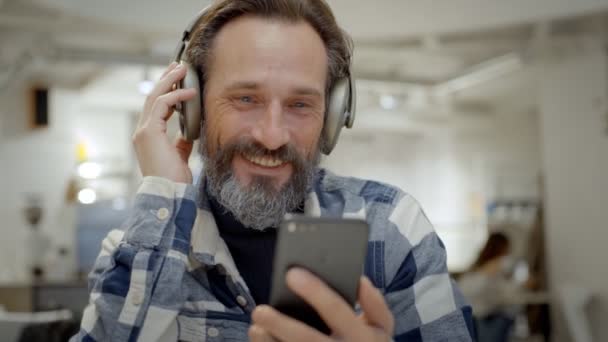 Hombre mayor guapo mira vídeo en el teléfono inteligente — Vídeo de stock