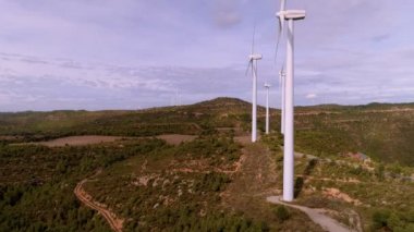 Gün batımında dağ manzarasında rüzgar türbini çiftliği