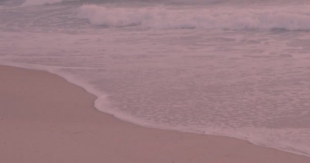 Olas de surf con espuma en la playa de arena rosa atardecer — Vídeos de Stock