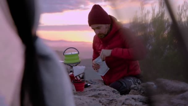 Mann kocht Kaffee beim Zelten bei Sonnenuntergang — Stockvideo