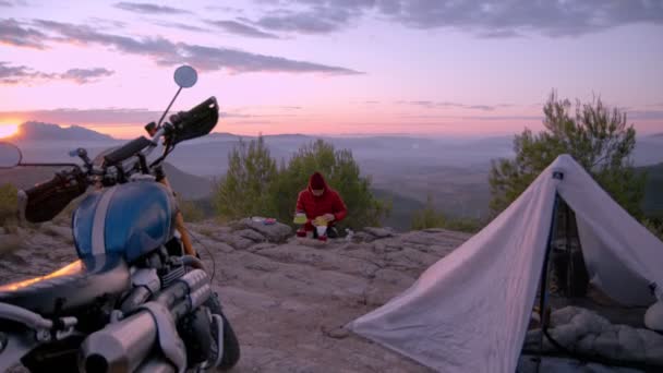 L'homme fait du café en campant au coucher du soleil — Video