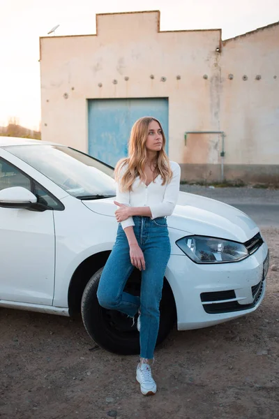 Milenyum kızı beyaz arabanın yanında duruyor. — Stok fotoğraf