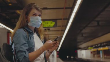 Coronavirus maskesiyle metro durağında genç bir kadın.