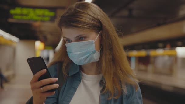 Mujer joven en la parada de metro en la máscara facial coronavirus — Vídeo de stock