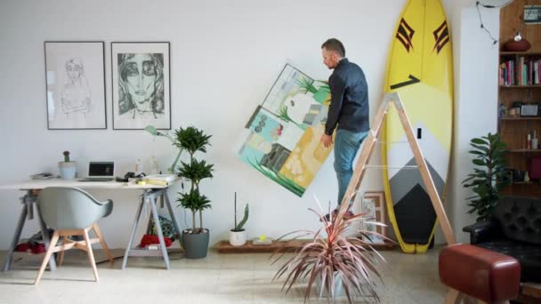 Pasangan kreatif menggantung lukisan di apartemen modern — Stok Video