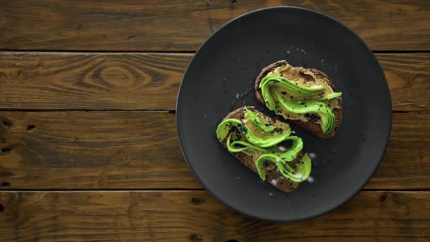 Vue de dessus sur sel de mer saupoudrer de pain grillé à l'avocat — Video