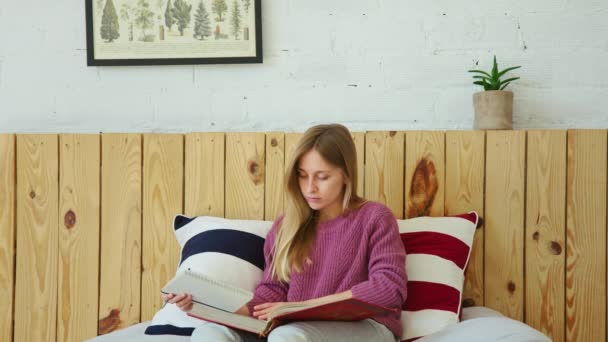 Ung söt student studerar fjärr för bok i sängen — Stockvideo