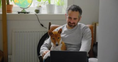 Adam ve köpeği dizüstü bilgisayardan video izliyorlar.