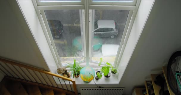 Vista sobre la calle gris y lluviosa a través de una ventana alta — Vídeo de stock