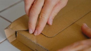 Kadın posta yoluyla teslim edilen karton kutuyu açıyor.
