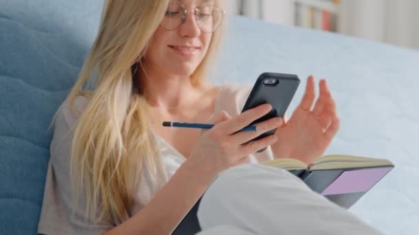 Fiatal csinos nő használja okostelefon kanapén otthon