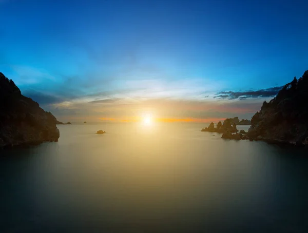 Long exposure seascape at sunset\sunrise. The sun goes down, surrounded by a halo and clouds. View of the cliff into the sea and distant islands. The backlight sunbeam. Paleokastrica. Corfu. Greece. — Foto de Stock
