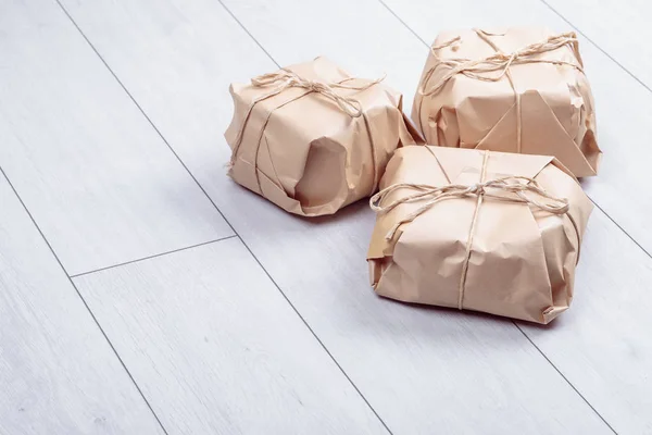 Geschenken verpakt in ambachtelijke papier pakket gebonden een touw op een wit eiken d — Stockfoto