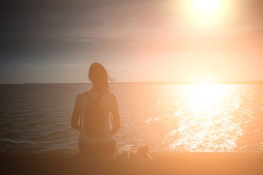 Kız sahil deniz taş dolgu üzerinde oturur ve bakar 