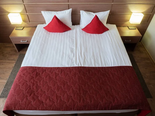 Vacker säng med röda kuddar i rummet — Stockfoto