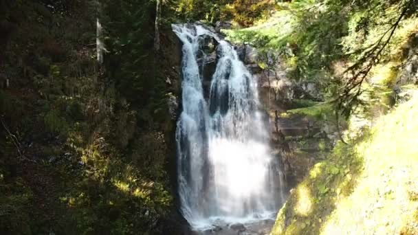 Una hermosa cascada grande fluye sobre piedras rocosas en el bosque y el sol se ha puesto maravillosamente sobre él . — Vídeos de Stock