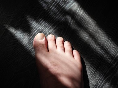 Erkekler, güneşin aydınlattığı ahşap zeminde yürür.