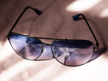 Yatağın üzerinde güzel güneş gözlükleri var ve güneş onların üzerinde parlıyor.