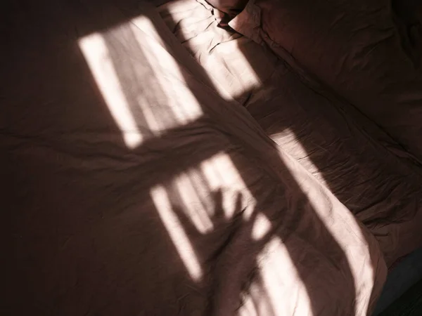 Mooie schaduw van het raam en hand op het bed van de ochtendzon — Stockfoto