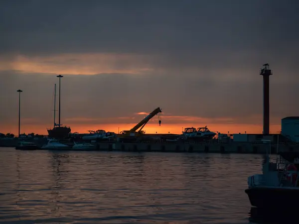 Um guindaste no cais do mar contra o pôr do sol em Sochi — Fotografia de Stock