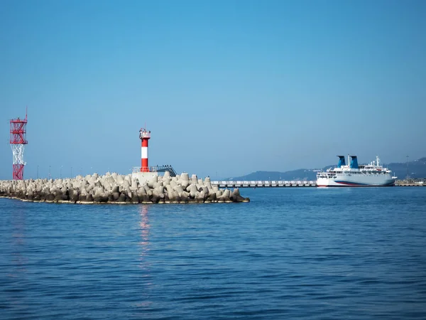 Red lighthouse with birds on a pier in the sea — Stock Photo, Image