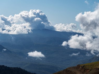 Mavi gökyüzü ve bulutları olan dağlık bir bölgenin üst görüntüsü