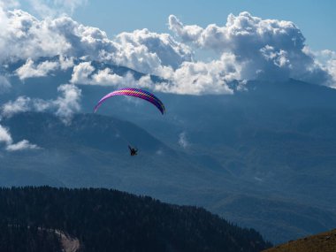 Paraglider bulutların üzerinden uçar dağların üzerinden ve ormanın üzerinden