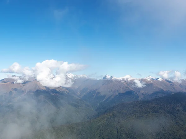 Вид на гірську долину зі засніженими вершинами в легкому хмарному тумані — стокове фото