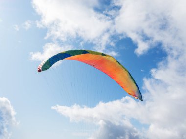 Mavi gökyüzü ve bulutlardan oluşan bir arka planda uçan paraglider. Kopyalama