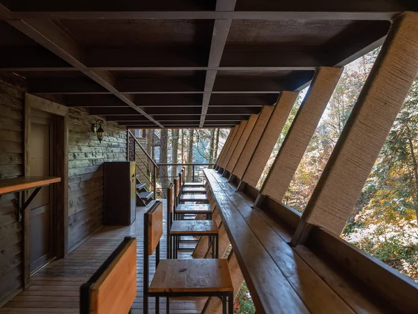 The balcony of the forest cafe is made of wood with wooden furniture. Inside view