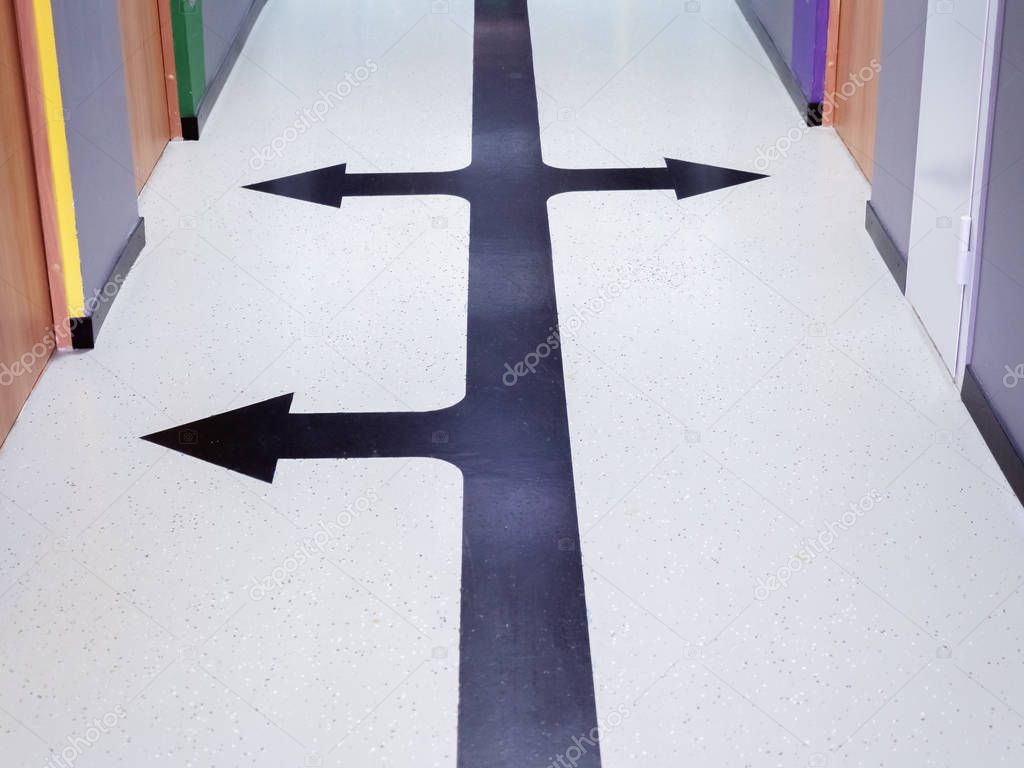 A black arrow drawn painted on the floor in the hallway points in different directions to the doors