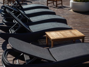 Siyah hasır güneş şezlongları sokağın ahşap platformunda dururlar.