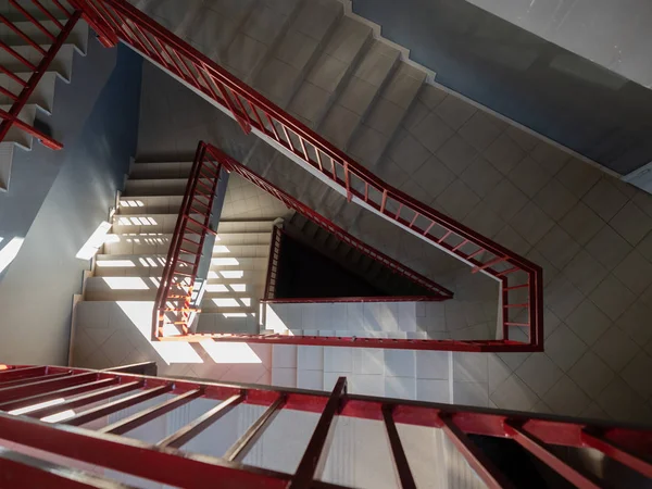 Perspective view of a beige staircase in the staircase with red railing leading to the bottom. — ストック写真