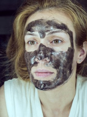 Yüzünde ince siyah şeffaf bir maske olan bir kızın yakın plan fotoğrafı.