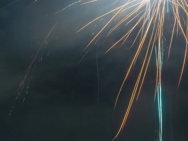 Close-up photo of a fragment of a bright colored firework similar to long ribbons against a foggy sky — Stock Photo, Image