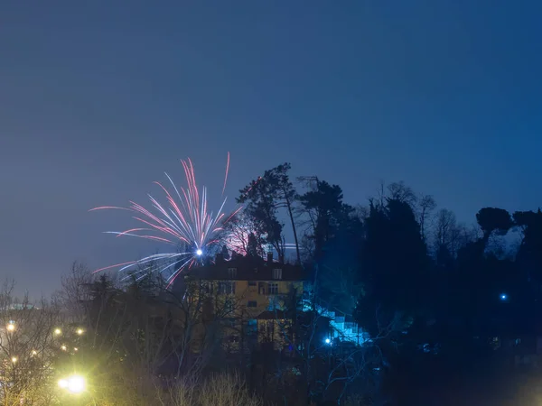 Helles Feuerwerk in der Nähe des Daches eines gelben Hauses vor blauem Himmel und Bäumen — Stockfoto