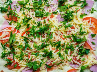 Jambon, domates rendelenmiş peynir ve doğranmış bitkilerle pişirmek için hazırlanmış bir yemek.