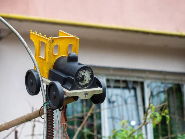 Plastik sarı eski oyuncak araba bulanık bir arka planda metal parmaklıklara bağlanmış. — Stok fotoğraf