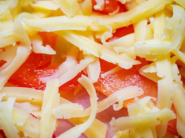 Bir sürü rendelenmiş peynir serpiştirilmiş domates ve jambonun yakın plan fotoğrafı.